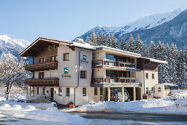 Haus Dschulnigg im Sonnenschein mit schneebedeckten Bergen und Natur im Hintergrund © Lukas Budimaier Haus Dschulnigg im Sonnenschein mit schneebedeckten Bergen und Natur im Hintergrund
