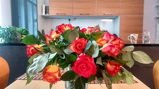 Blumenstrauß in Vase, dahinter eine Küche.