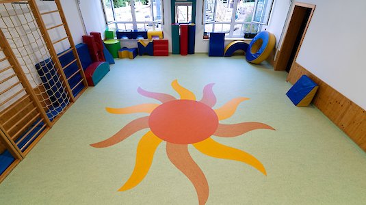 Bewegungsraum Kindergarten mit Sonne im Bodenbelag Bewegungsraum Kindergarten mit Sonne im Bodenbelag